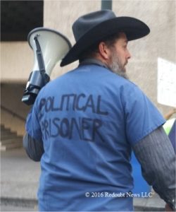 Protester John Lamb from Bozeman, MT wears blue scrubs during rally on Friday night. Photo: Redoubt News